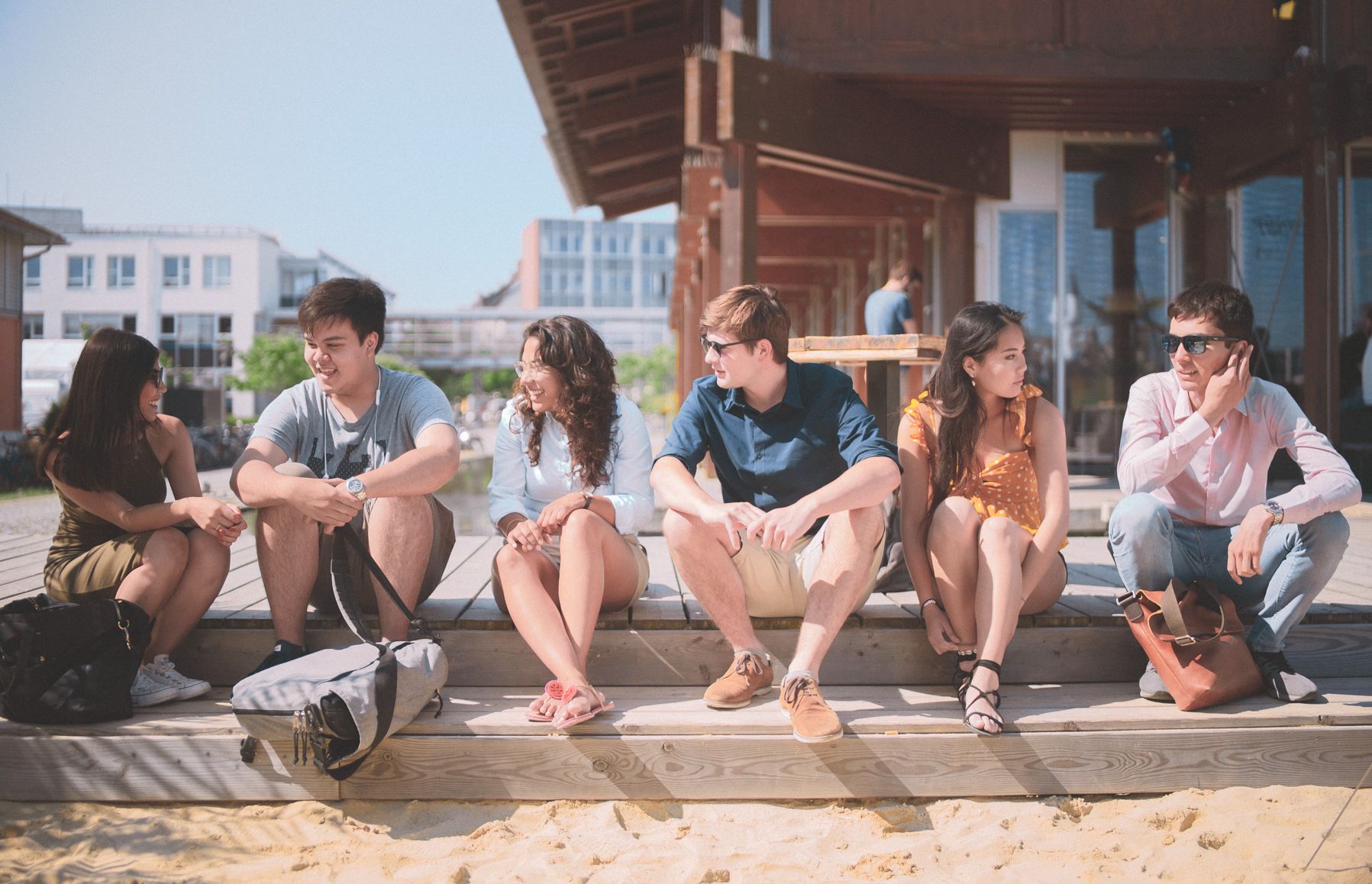 Eine Gruppe Studierender sitzen in der Sonne an der Strandbar