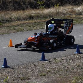 Ein Rennwagen auf einer Asphalt-Strecke zwischen Pylonen.