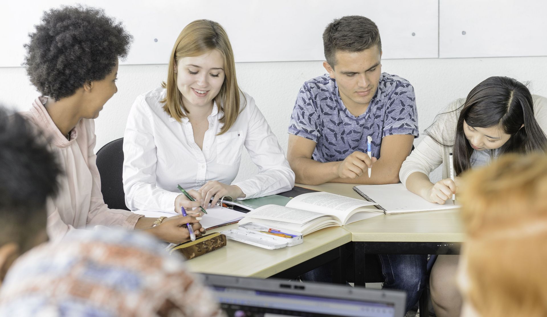 Eine Gruppe Studierender sitzen in einem Kurs und sind am lernen