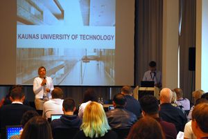 Frau steht mit Mikrofon vor sitzendem Publikum. Auf der Präsentation hinter ihr steht Kaunsas University of Technology