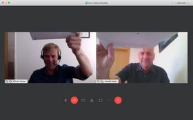 Screenshot aus einer Online-Sitzung: eine Sequenz zeigt eine Person, die ein Dokument anreicht, die andere Sequenz, dass eine Person ein Dokument annimmt an, eine 