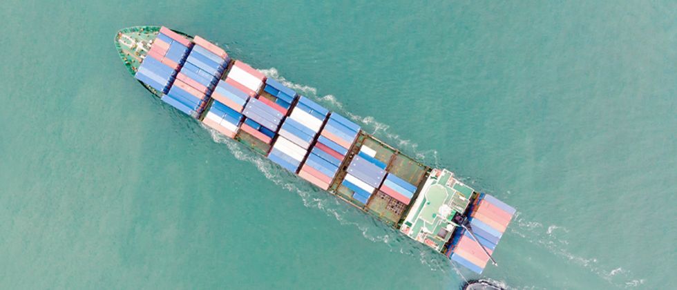 Luftaufnahme eines Containerschiffes mit Begleitboot.