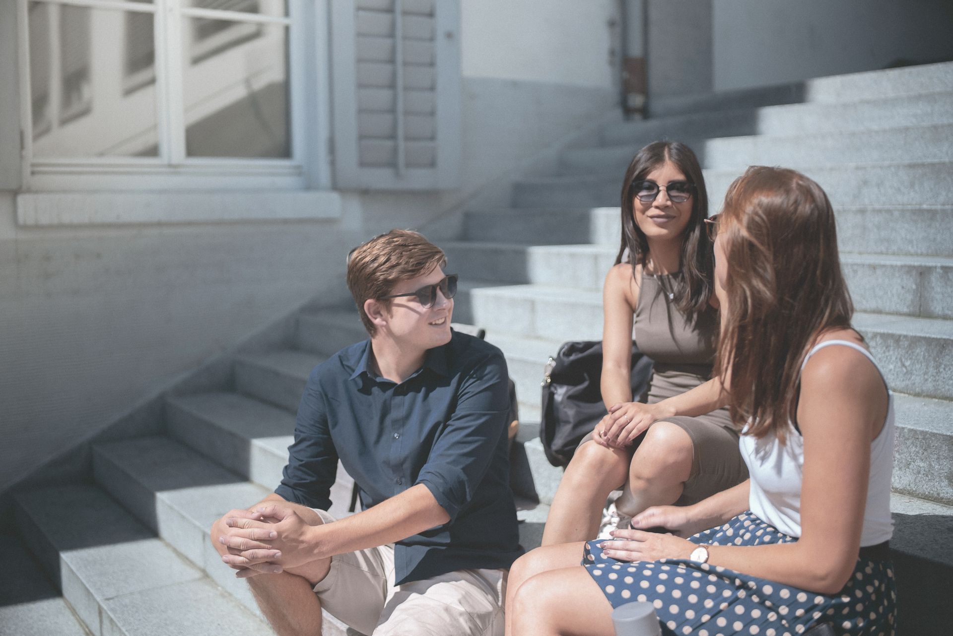 Eine Gruppe STudierender unterhält sich vor dem Hochschulgebäude