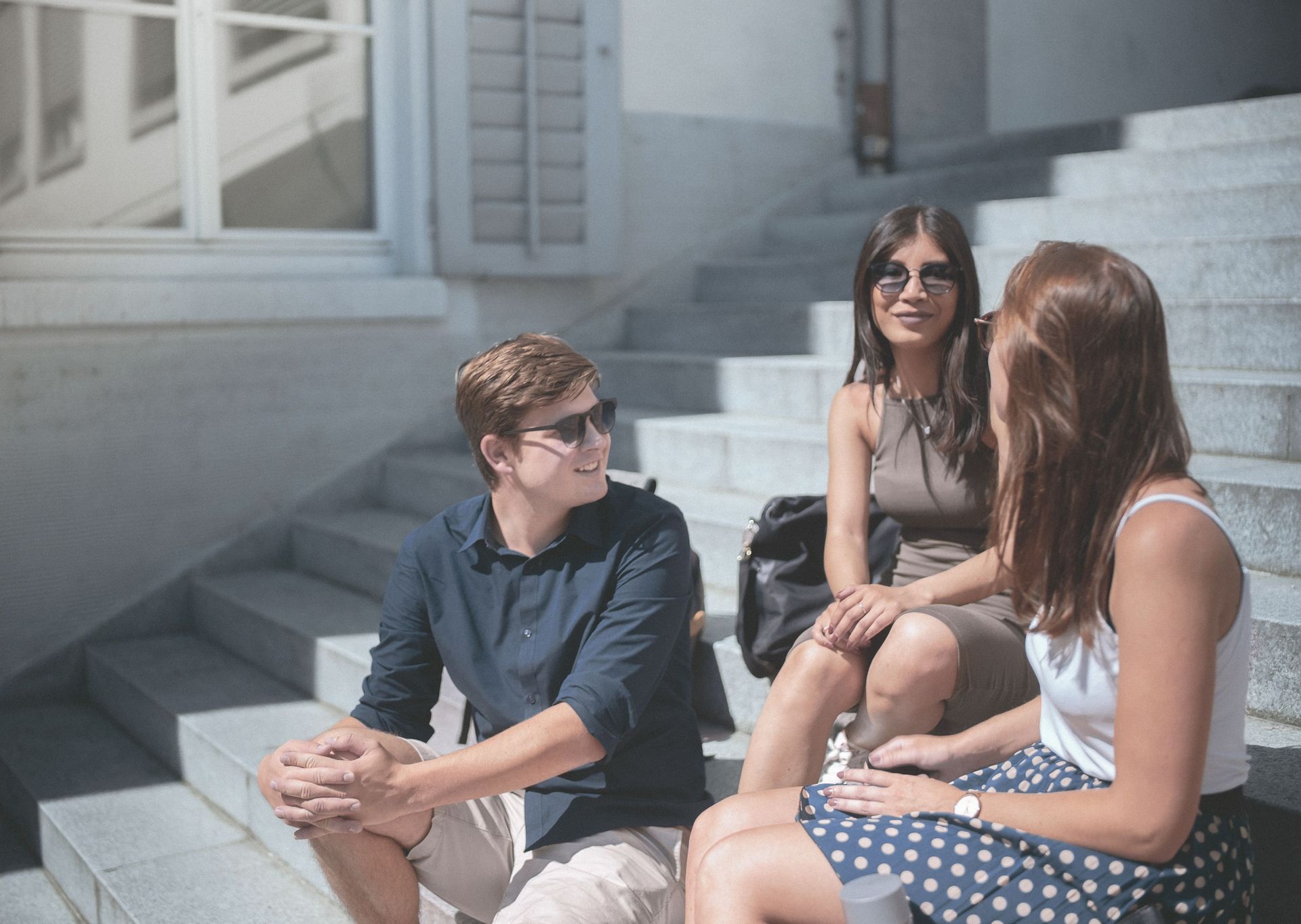 Eine Gruppe STudierender unterhält sich vor dem Hochschulgebäude