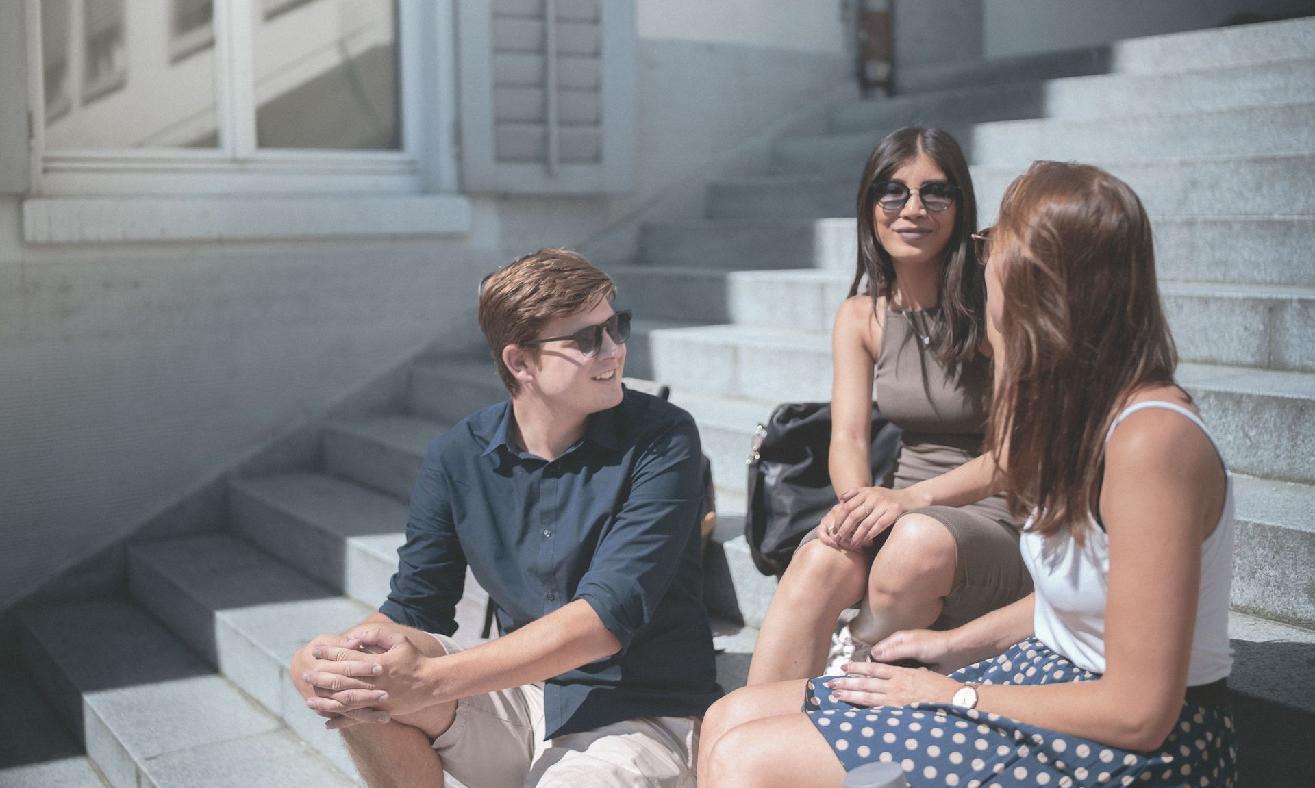 Eine Gruppe STudierender unterhält sich vor dem Hochschulgebäude