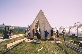 Elf Personen ziehen die Vorderseite einer kleinen Holzkapelle hoch