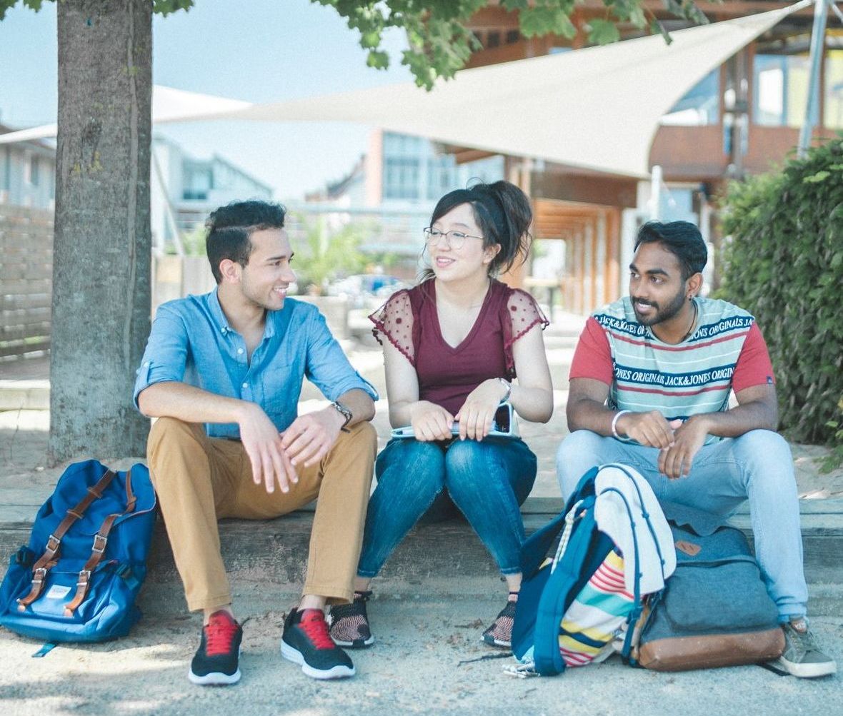 Studierende sitzen an der Standbar und unterhalten sich