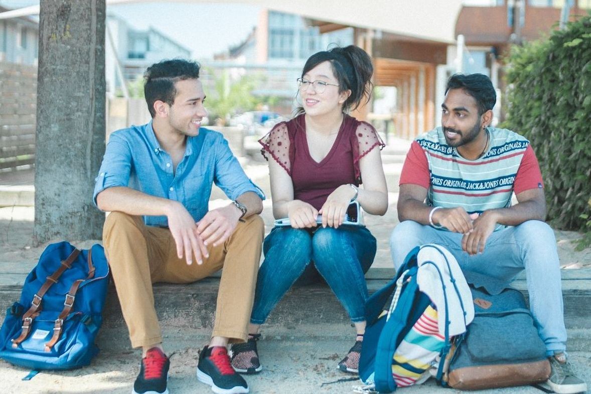 Studierende sitzen an der Standbar und unterhalten sich