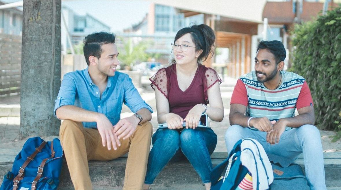 Studierende sitzen an der Standbar und unterhalten sich