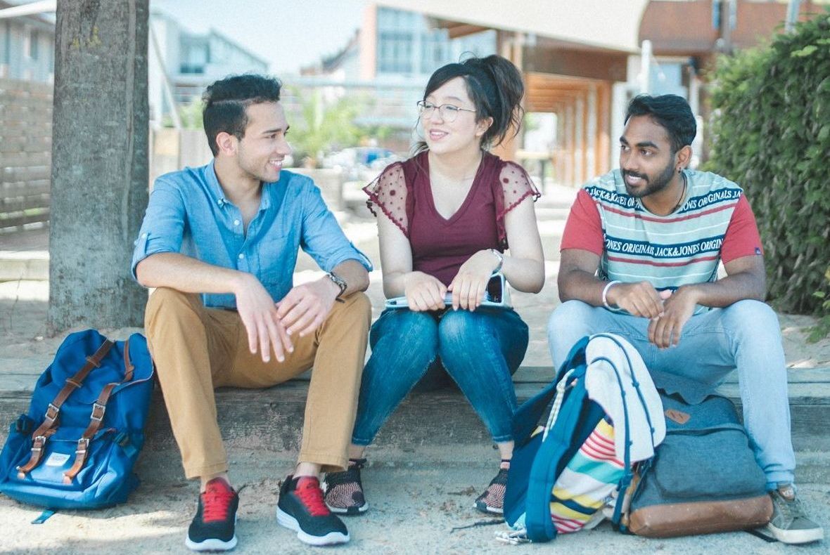 Studierende sitzen an der Standbar und unterhalten sich