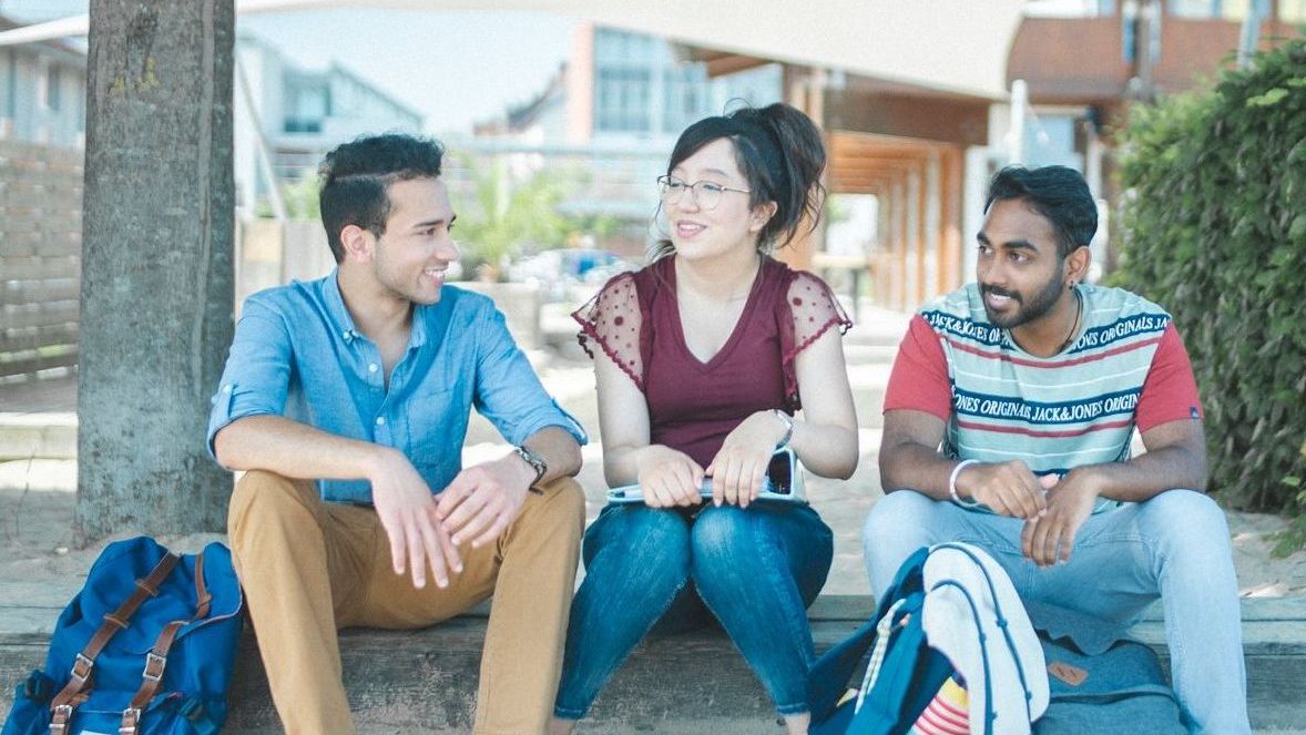 Studierende sitzen an der Standbar und unterhalten sich