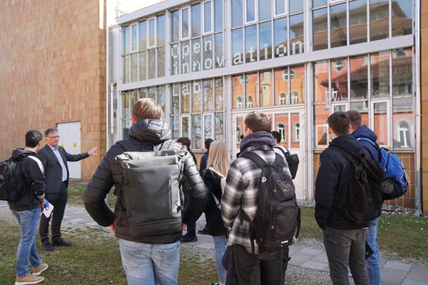 Vizepräsident Prof. Dr. Thomas Birkhölzer steht links von einer Gruppe. Rechts ist am Gebäude die Aufschrift "Open Innovation Lab" zu erkennen.