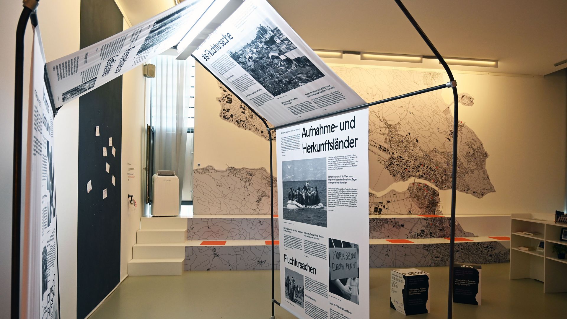Foto aus der Ausstellung; zu sehen ist eine Art Zelt mit Zeitungsausschnitten