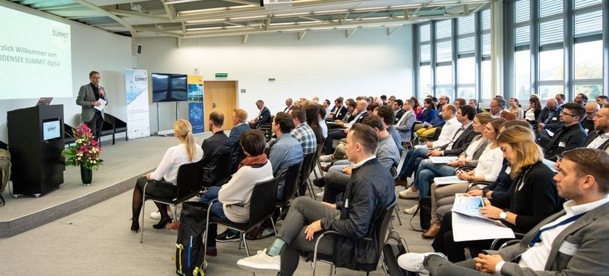 Blick in einen Vortragsraum mit Publikum. Klaus-Dieter Schnell, Geschäftsführer der Internationalen Bodensee-Konferenz (IBK), steht links am Rednerpult.