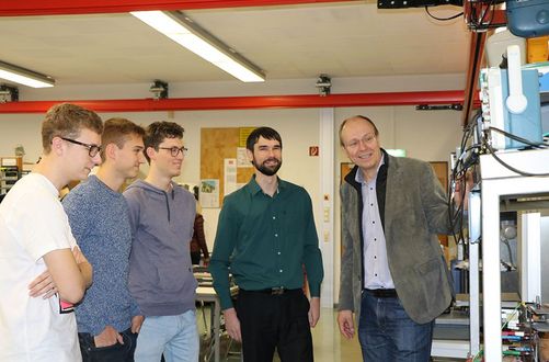 Prof. Dr. Gunter Voigt steht mit Studierenden im Labor zusammen. Zu Besuch und mit dabei ist Nelius Bekker, Lecturer im Bereich Electric Power Systems und Smart Grids sowie Leiter des Labors für Hochspannungstechnik an der University of Stellenbosch / ZA. Die University of Stellenbosch ist eine langjährige Partnerhochschule der HTWG in Südafrika mit erfolgreichem Austausch von Studierenden in beide Richtungen.