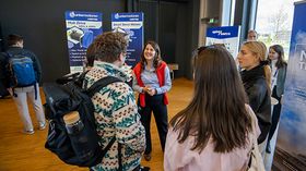 Gruppenfoto von Studierenden, die mit einer Ausstellerin sprechen