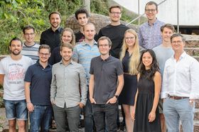 Eine Gruppe junger Menschen in sommerlicher Geschäftskleidung posiert im Freien auf einer Treppe fürs Foto.