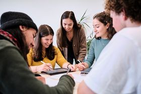 5 Studierende arbeiten an einem Tisch sitzend zusammen