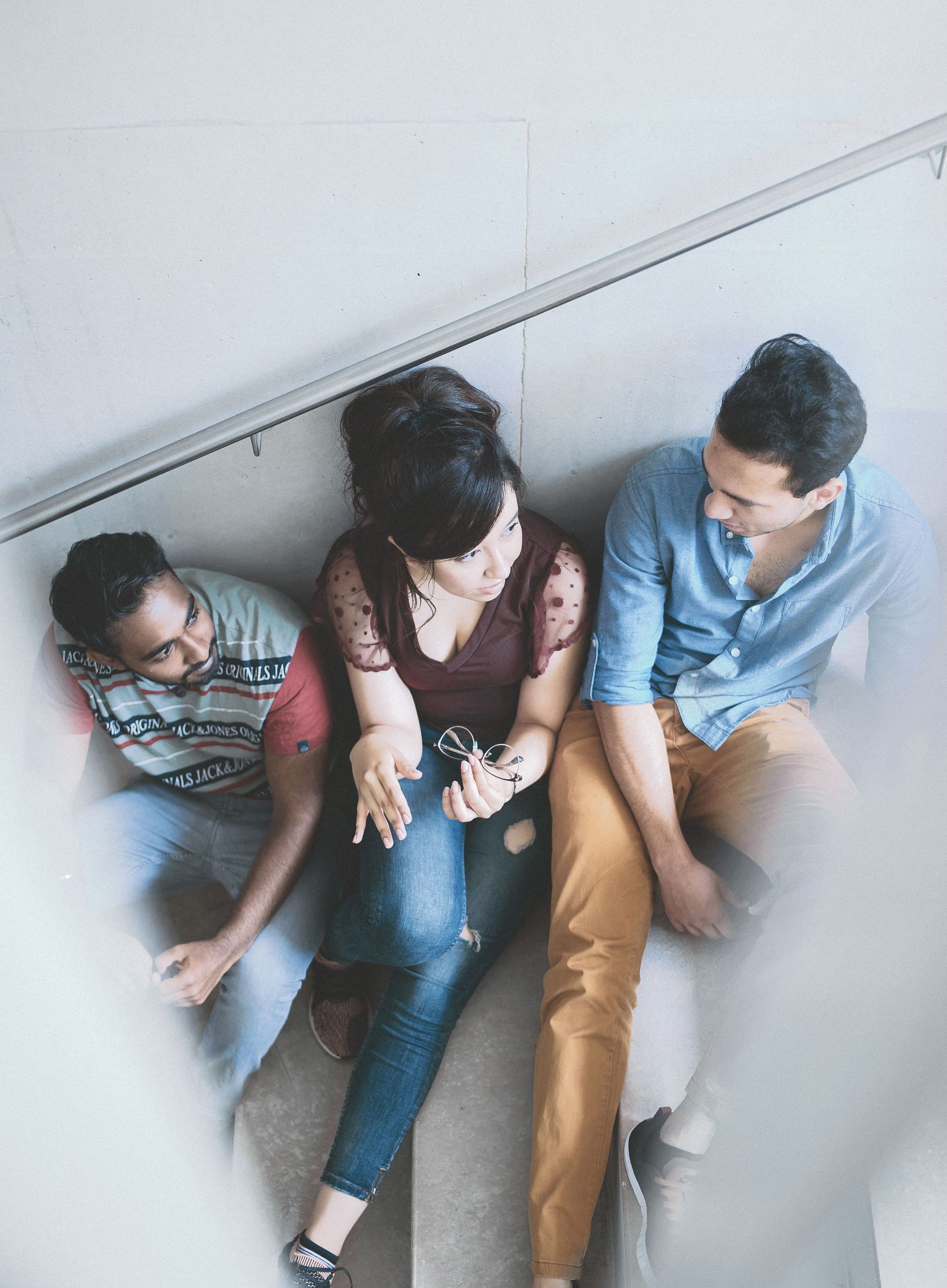 Three students are chatting while sitting on stairs