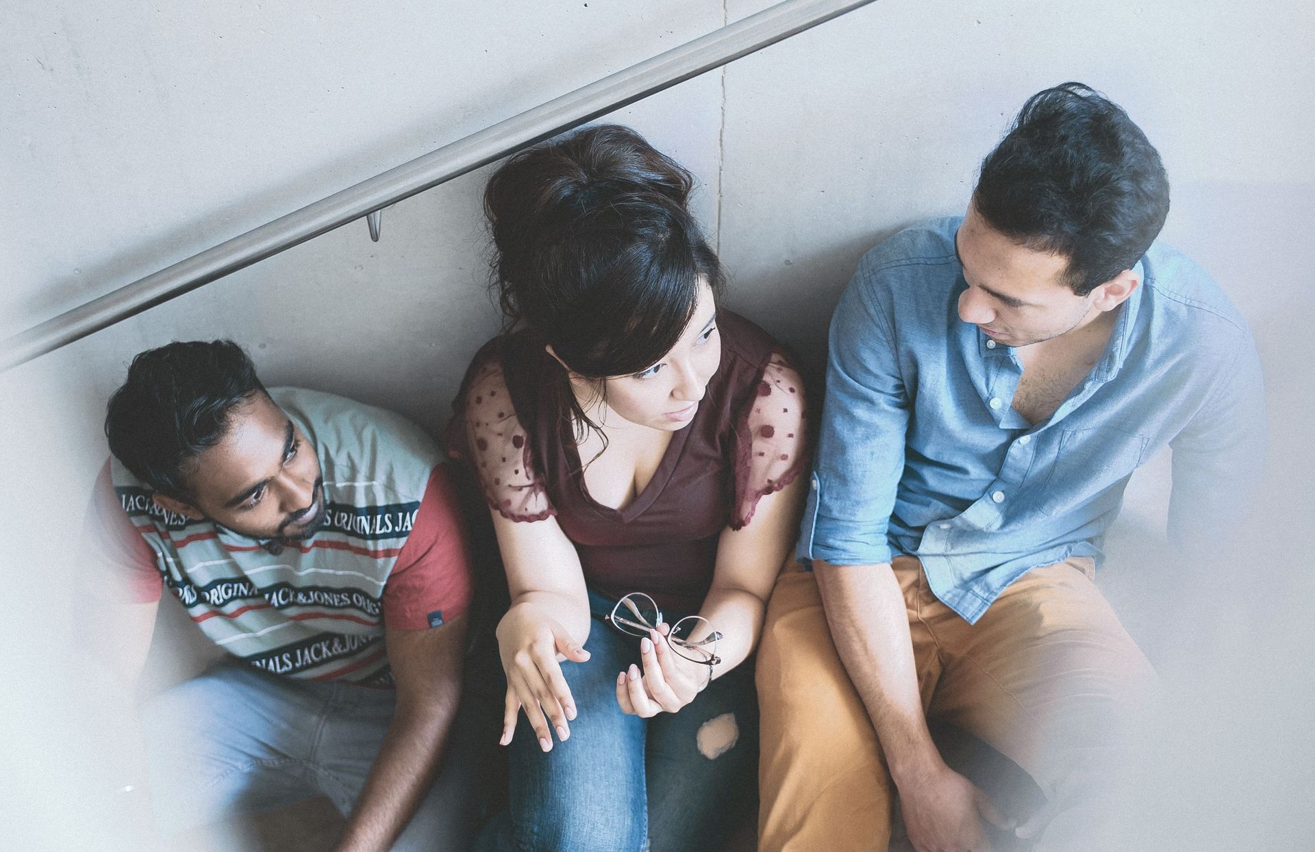 Drei Studierende sitzen im Gang der Hochschule und unterhalten sich