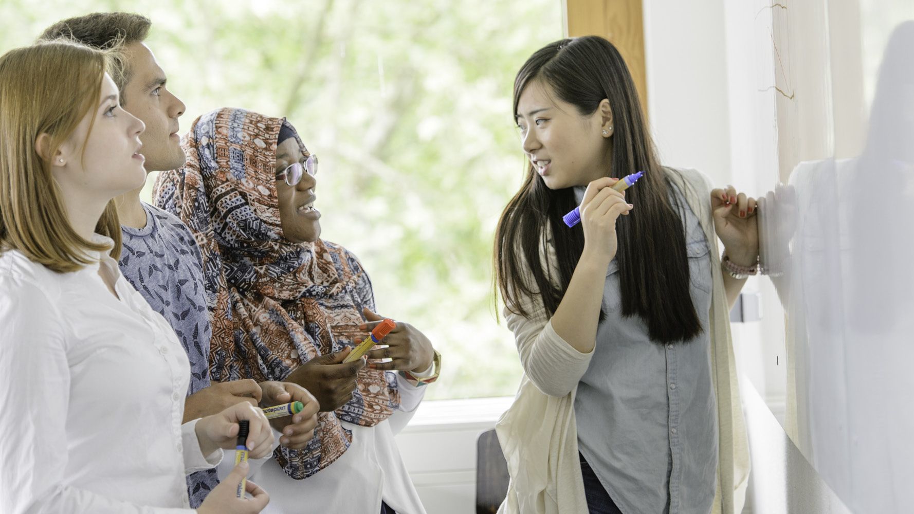 Eine Gruppe internationaler Studierenden stehen vor einer Tafel