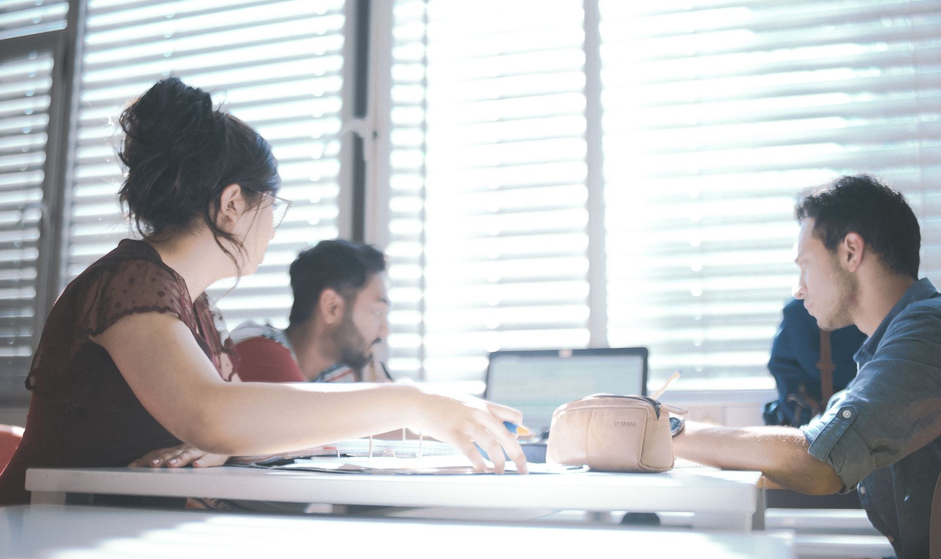 Eine Gruppe Studierender sitzen um einen Tisch und Arbeiten gemeinsam