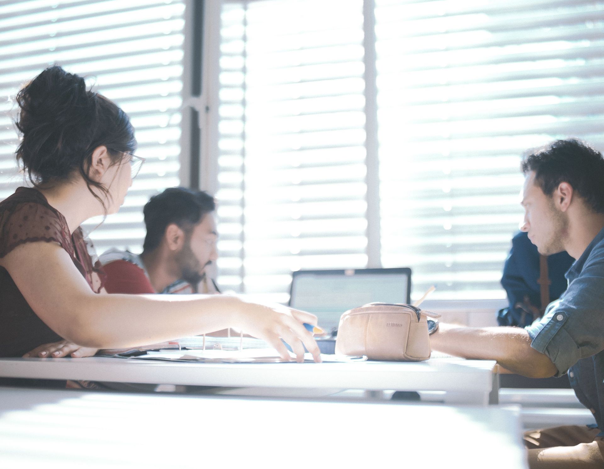 Eine Gruppe Studierender sitzen um einen Tisch und Arbeiten gemeinsam