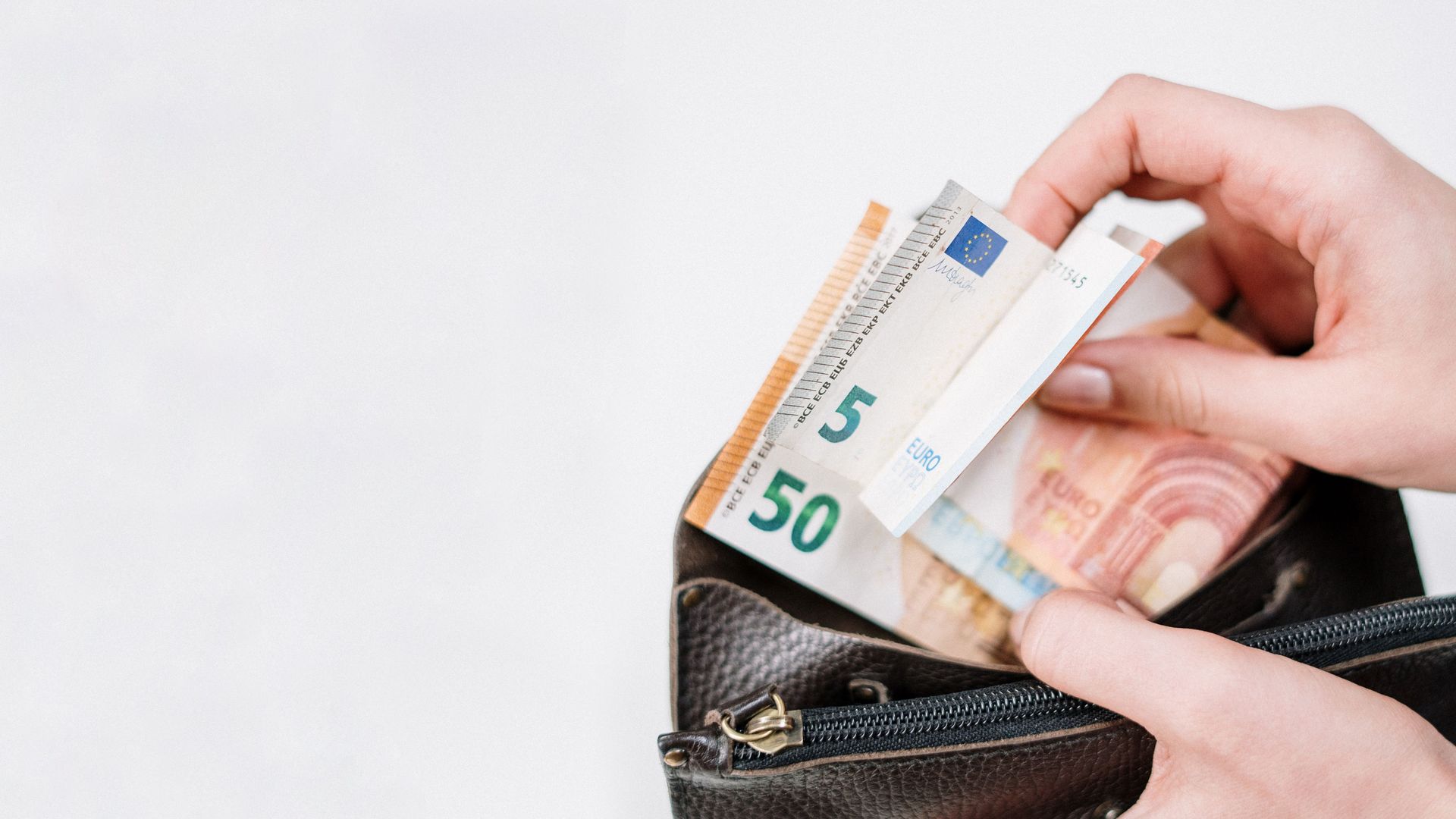 Jemand nimmt mehrere Euro-Scheine aus einer Geldbörse