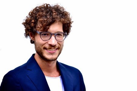 Alexander Heiser Alexander Heiser mit lockigen Haaren und blauen Anzug