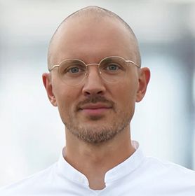 Das Porträtbild zeigt einen Mann mit Brille, der in die Kamera schaut