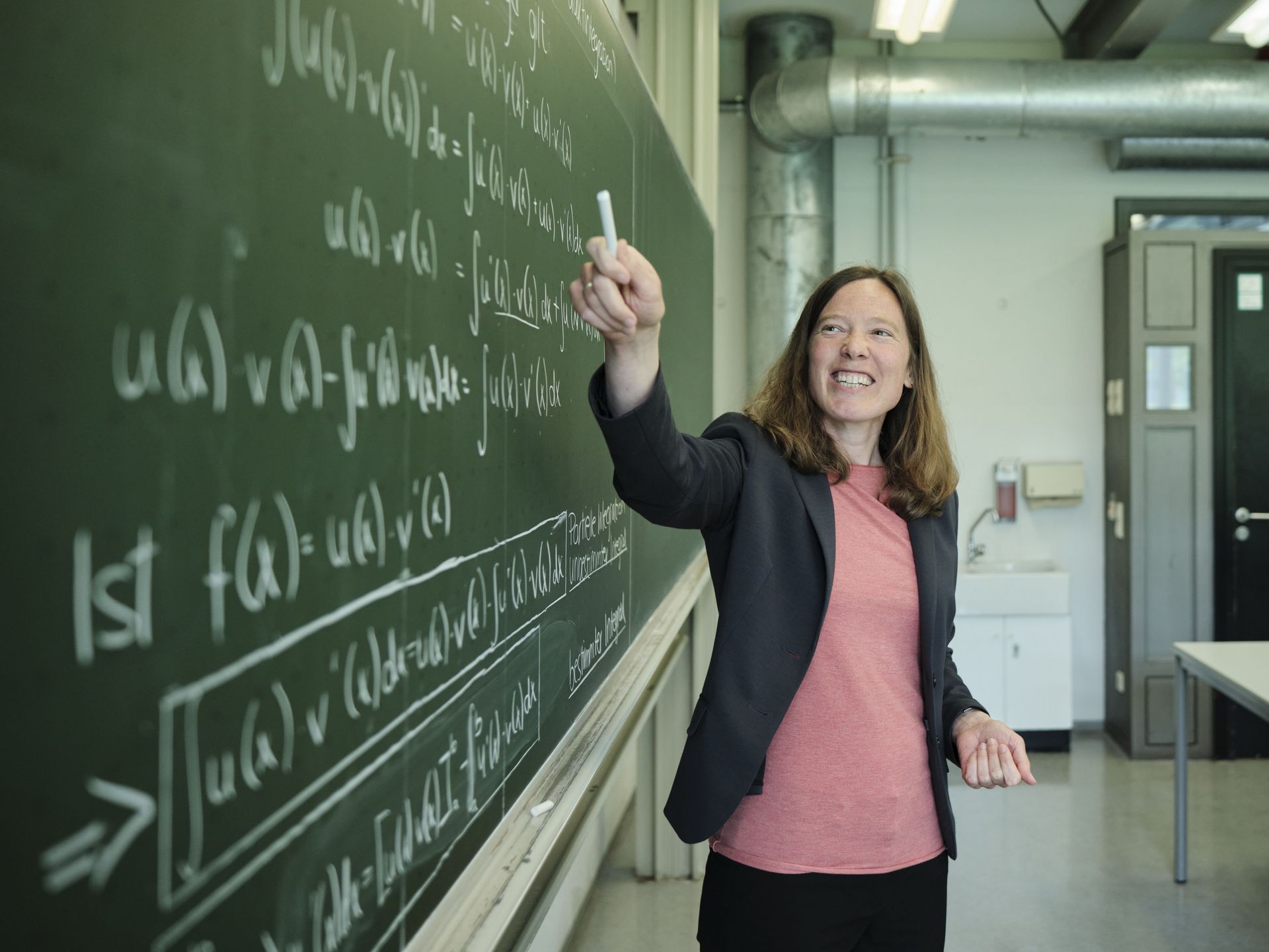 Motiverte Mathematikdozentin an der Tafel. 