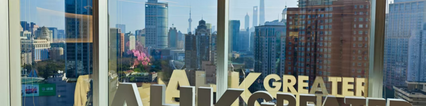 Man sieht die Shanghaier Skyline aus dem Fenster der AHK, der Schriftzug AHK Greater China spiegelt sich im Fenster. 