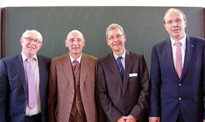 Vier formal gekleidete Männer stehen nebeneinander.