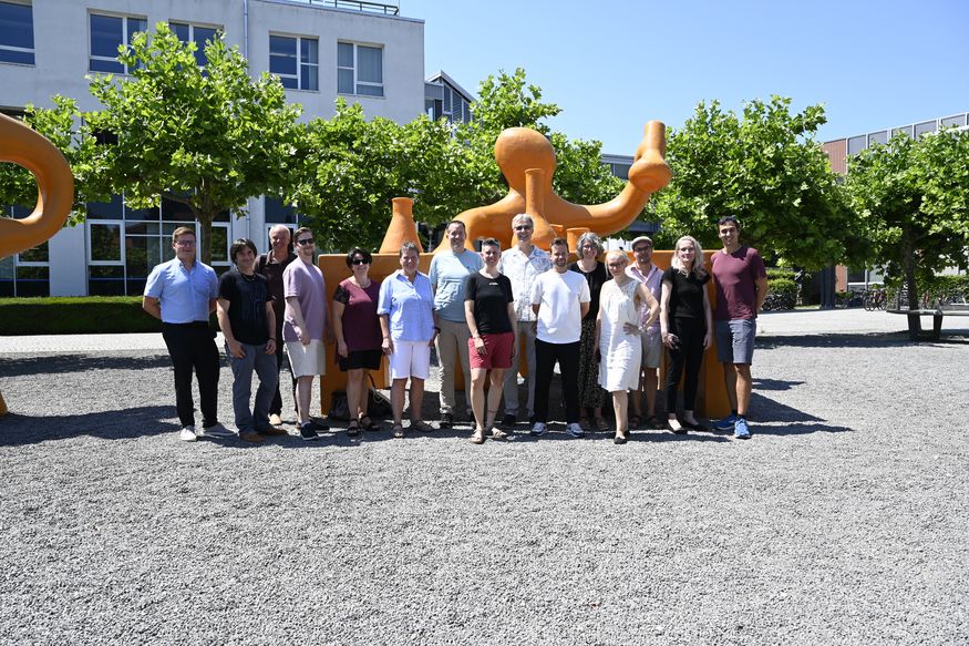 Eine Gruppe Menschen steht auf dem Innenhof der Hochschule Konstanz und lacht in die Kamera