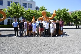 Eine Gruppe Menschen steht auf dem Innenhof der Hochschule Konstanz und lacht in die Kamera