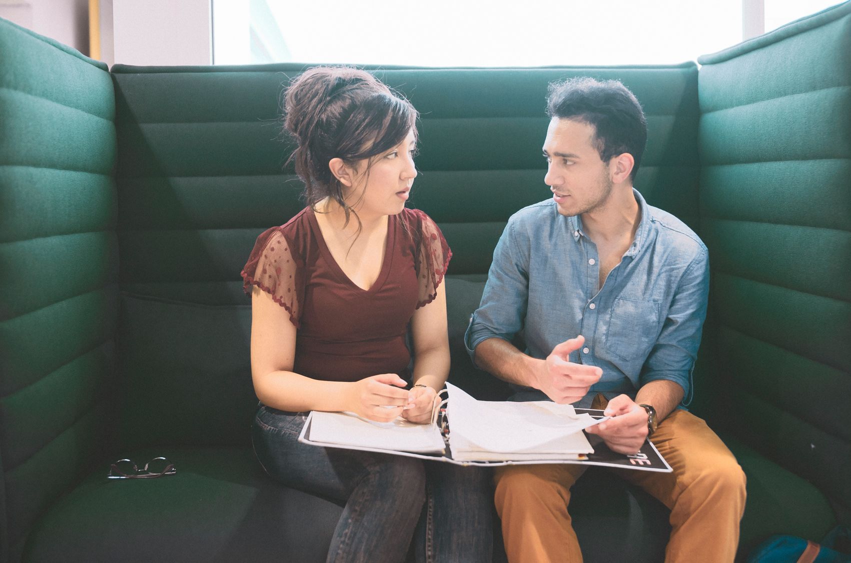 Zwei studierende sitzen nebeneinander in der Bibliothek und diskutieren miteinander