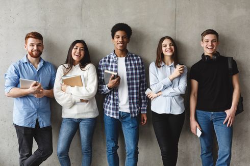 Fünf Studierende lehnen an einer Wand und blicken in die Kamera.