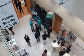 Das Foyer der Firmenmesse mit Ausstellern und Besucher*innen von oben. 