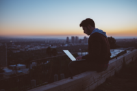 Lange Nacht des Schreibens: Student mit Laptop auf nächtlichem Häuderdach