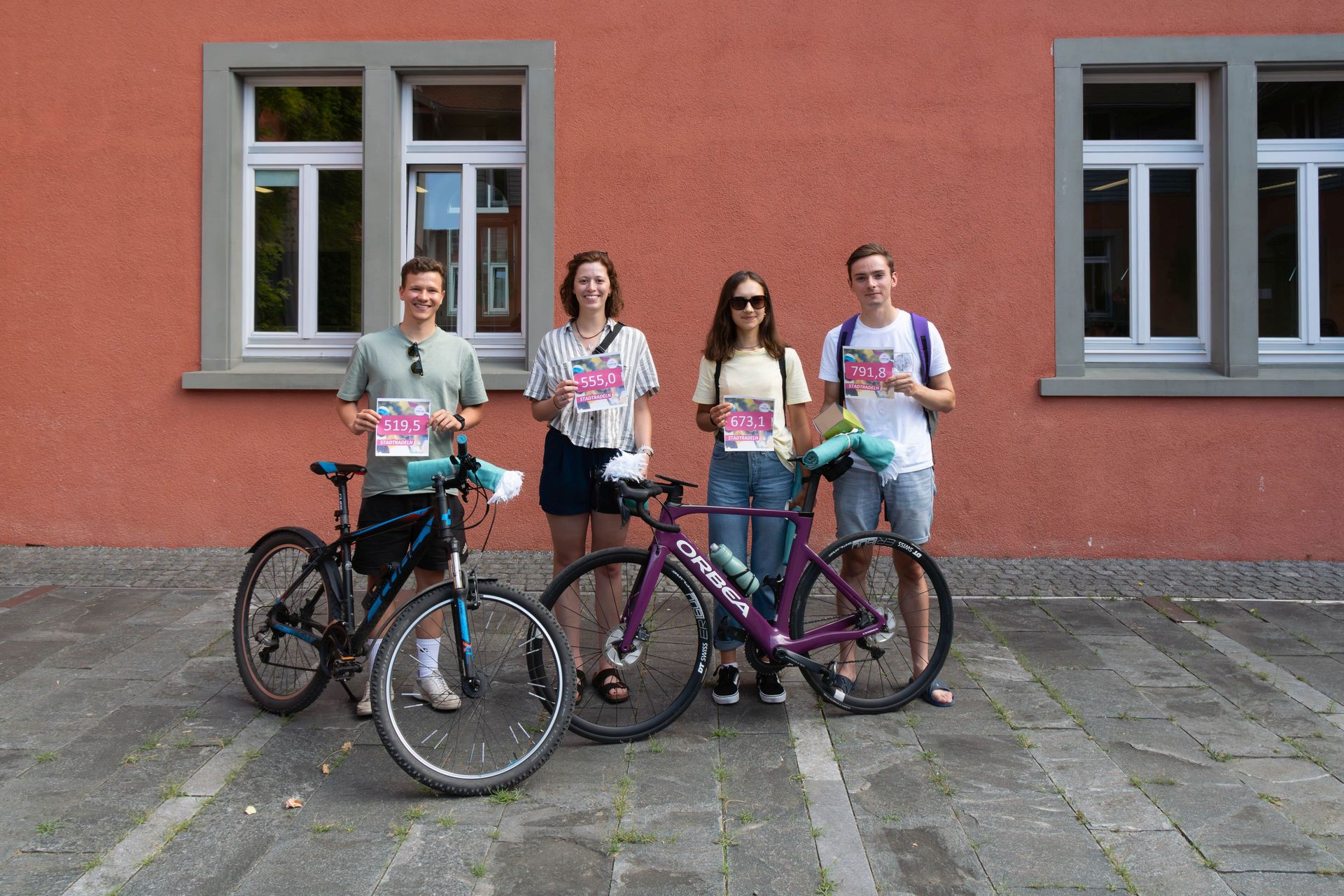 Vier Hochschulangehörige stehen mit ihren Fahrrädern und einem Schild mit der Zahl der zurückgelegten Kilometer zusammen. Die 5 stärksten Radelnden der Hochschule innerhalb des jährlichen Stadtradelns wurden mit kleinen Preisen bedacht. Einer der Gewinnenden fehlt im Bild.