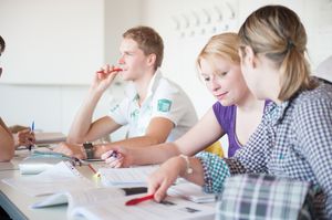 BWL-Vorlesung Drei Studierende sitzen in einer Vorlesung und besprechen eine Aufgabe.