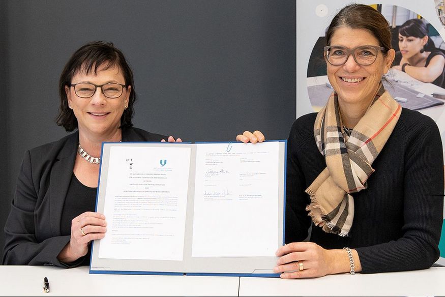 Zwei Frauen halten eine Urkunde zwischen sich in die Kamera, links HTWG-Präsidentin Prof. Dr. Sabine Rein, rechts Prof. Dr. Katrin Klodt-Bußmann, Vizepräsidentin wissenschaftliche Weiterbildung und Internationales.