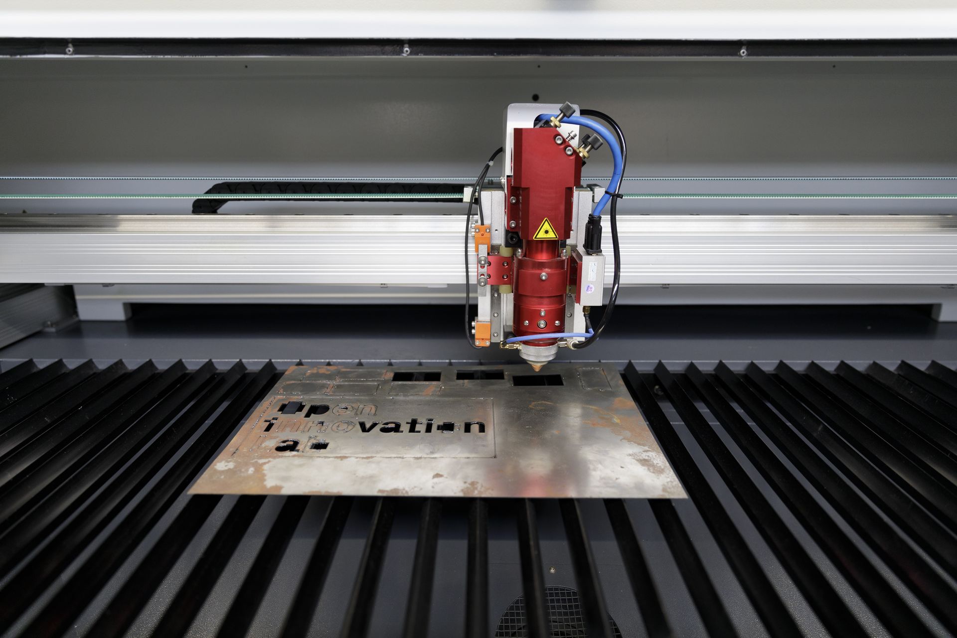 Ein Laserschneider schneidet den Schriftzug "OIL Innovation Lab" in eine Metallplatte.
