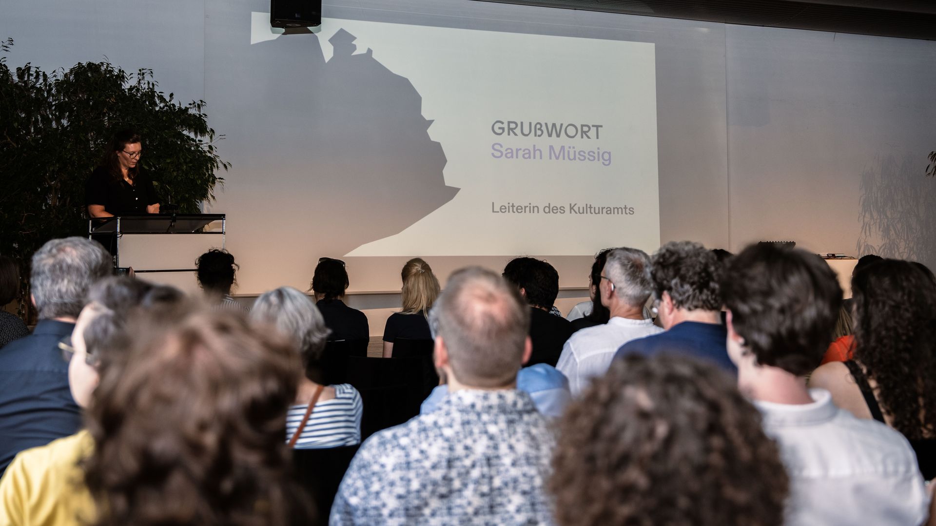 Foto: Kulturamtsleiterin Sarah Müßig bei ihrer Vernissagenrede; Publikum von hinten