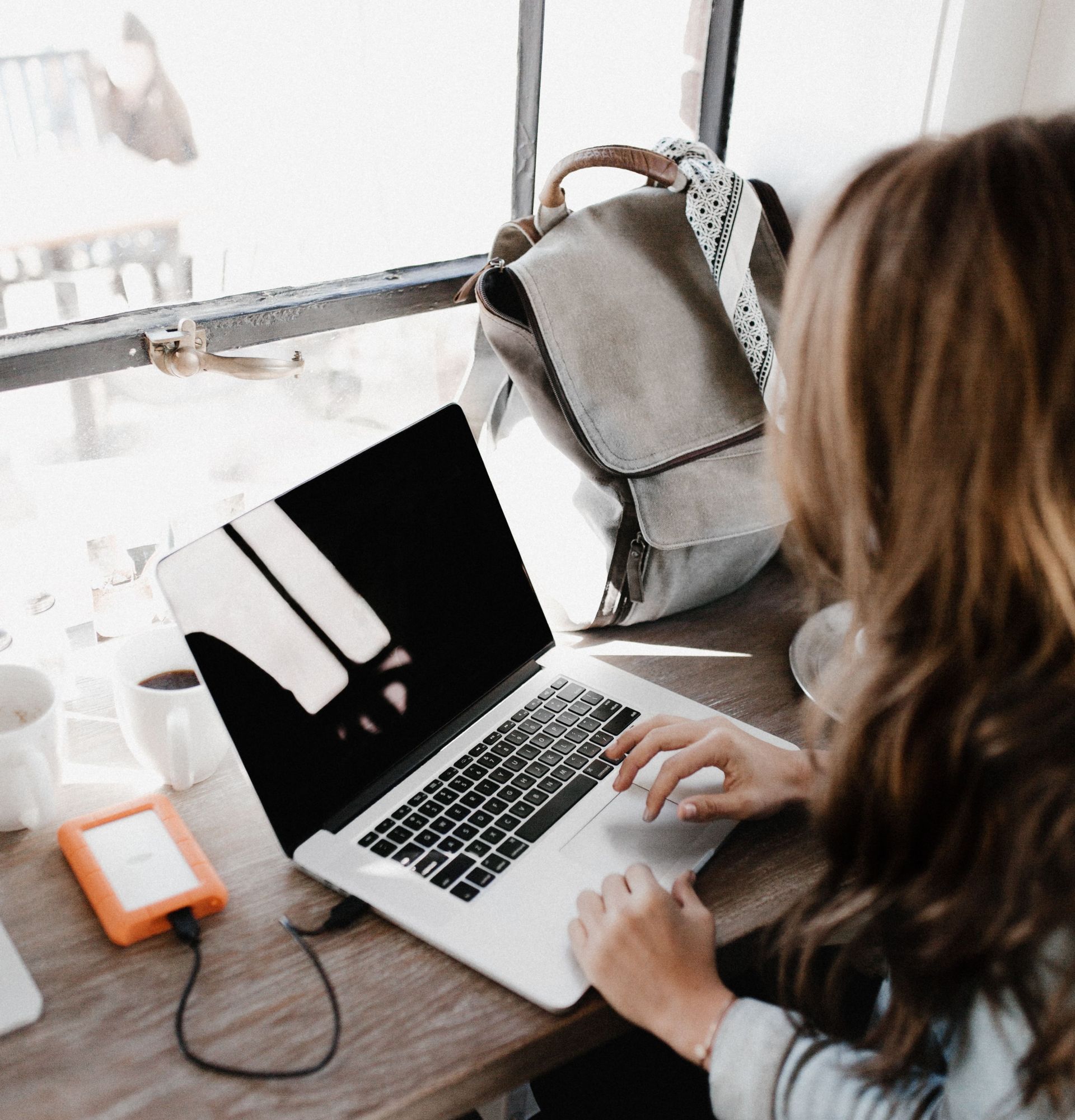 Eine junge Frau bearbeitet etwas an Ihrem Laptop