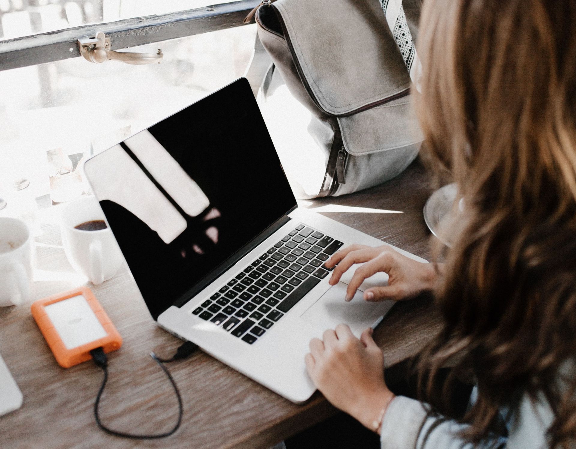 Eine junge Frau bearbeitet etwas an Ihrem Laptop