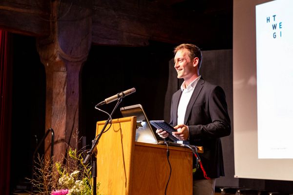 Absolvent Lukas Daumer steht am Rednerpult und spricht mit Blick ins Publikum.