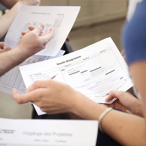 Nahaufnahme von mehreren Hönden die Zettel mit Gantt-Charts halten