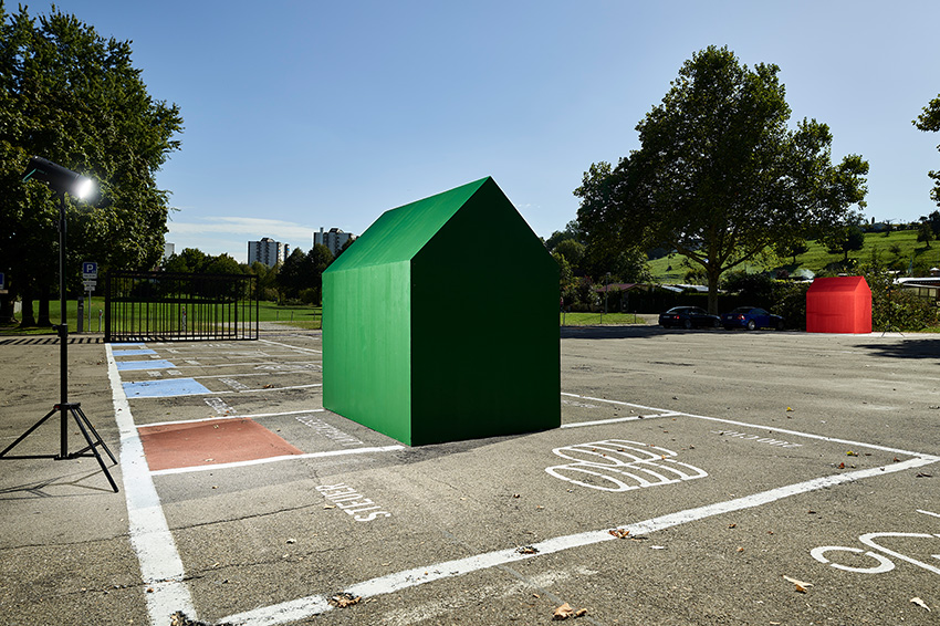 Foto einer grünen Hausfigur auf einem Platz.