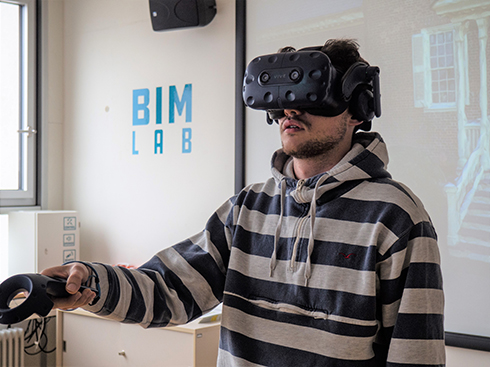 Student mit aufgesetzter VR-Brille und Controller in der Hand arbeitet im BIM LAB 